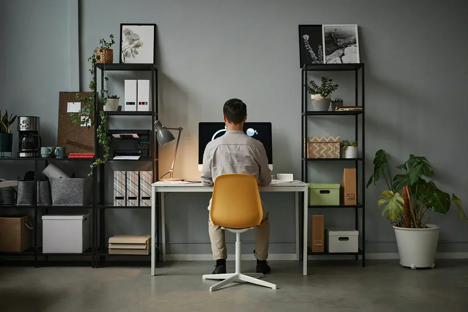 Homme de dos assis sur sa chaise de bureau en train de travailler