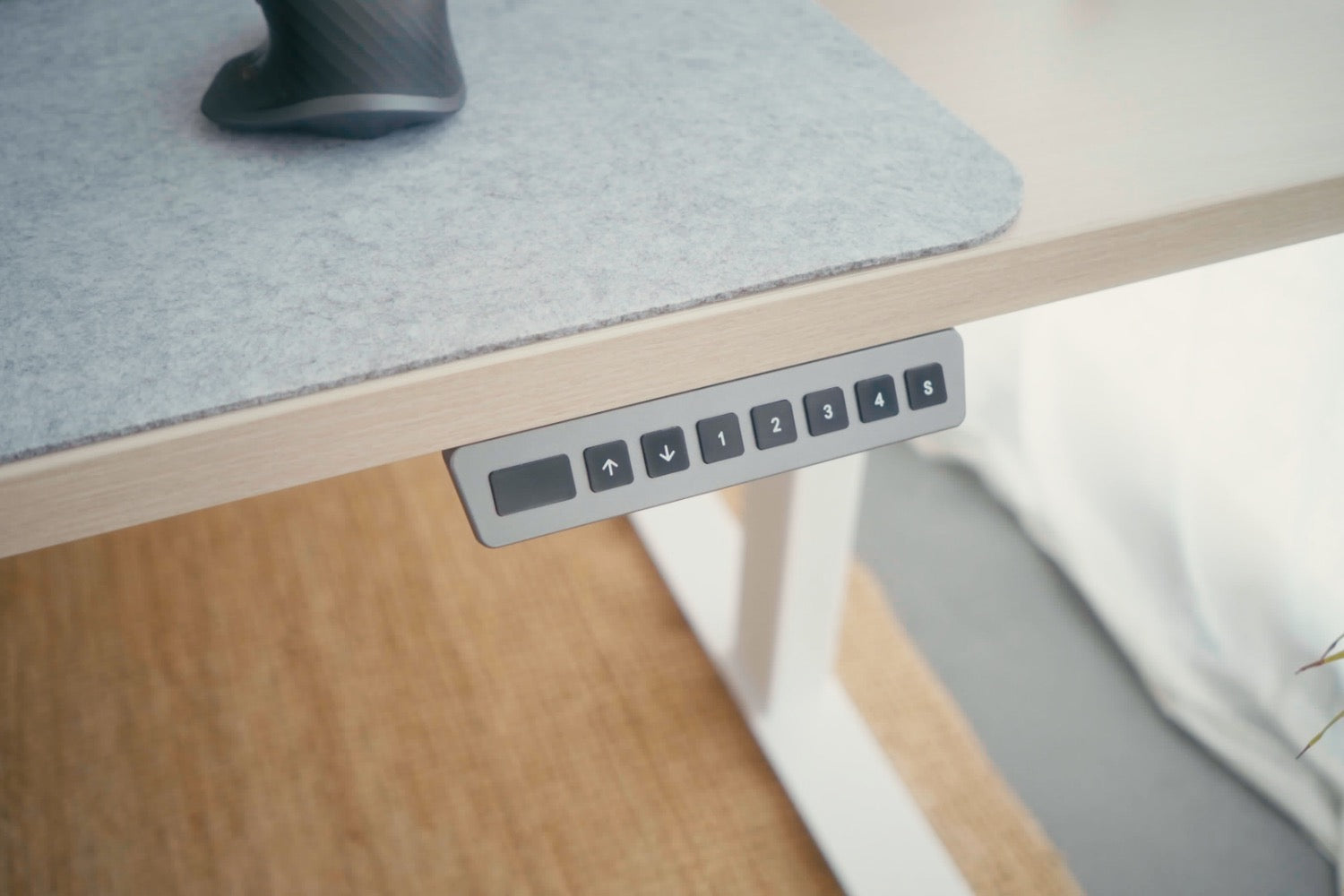 Bureau avec un zoom sur le boitier de commande qui aide le mouvement du bureau assis-debout