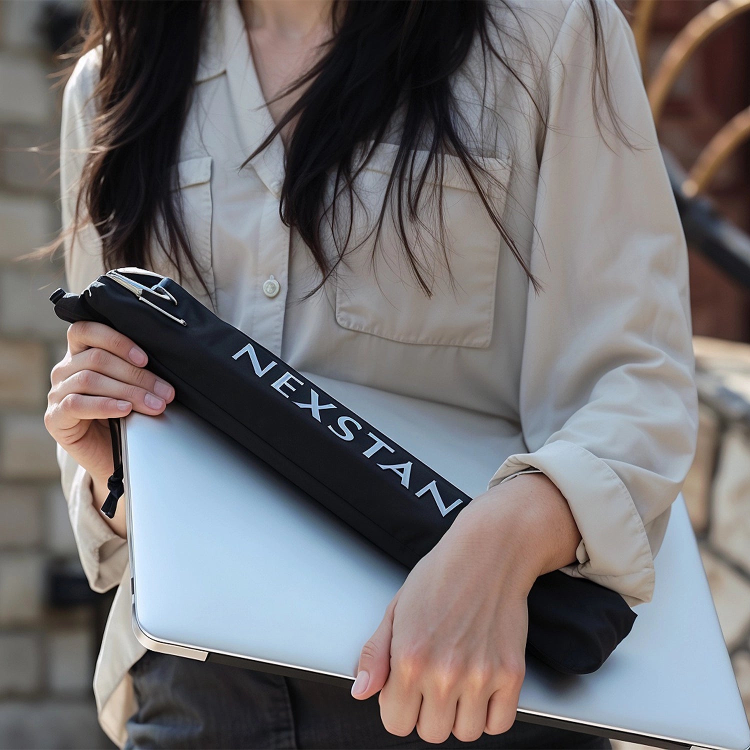 Femme dans la rue portant son ordinateur portable ainsi que son support d'écran correctement rangé qui montre la practicité de l'objet 