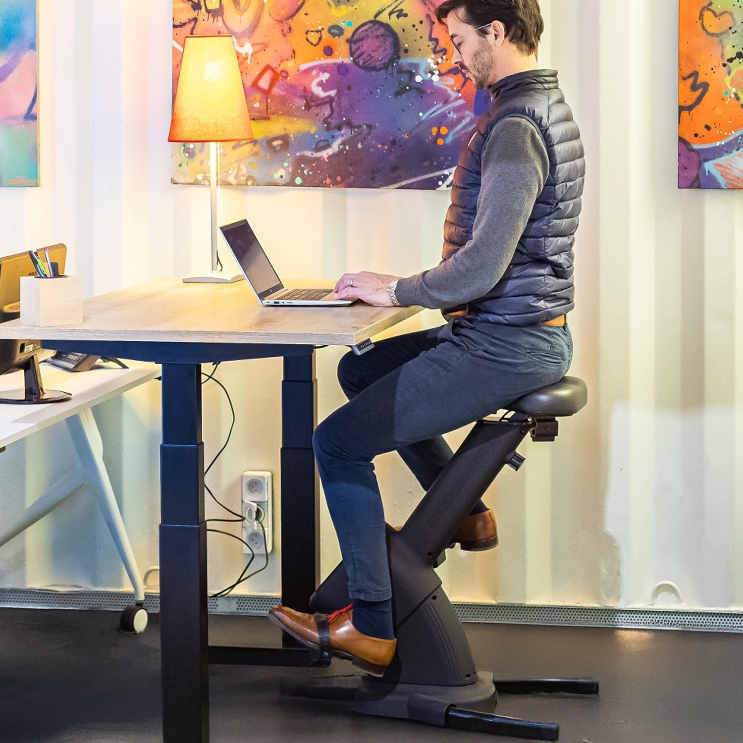 Homme installé sur son vélo de bureau travaillant sur son ordinateur posé sur le bureau